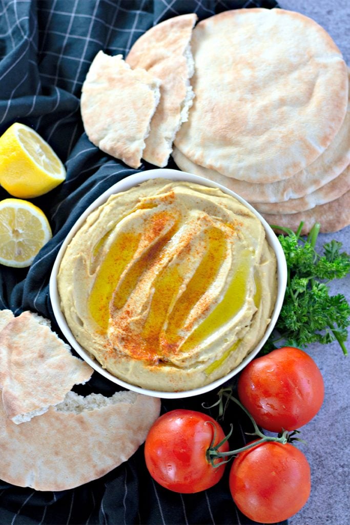 overhead of served hummus surrounded by pita bread