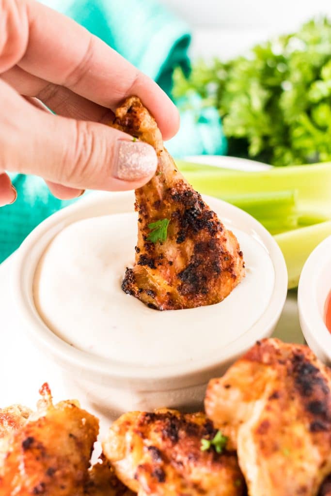 hand dipping a chicken wing into ranch dressing.