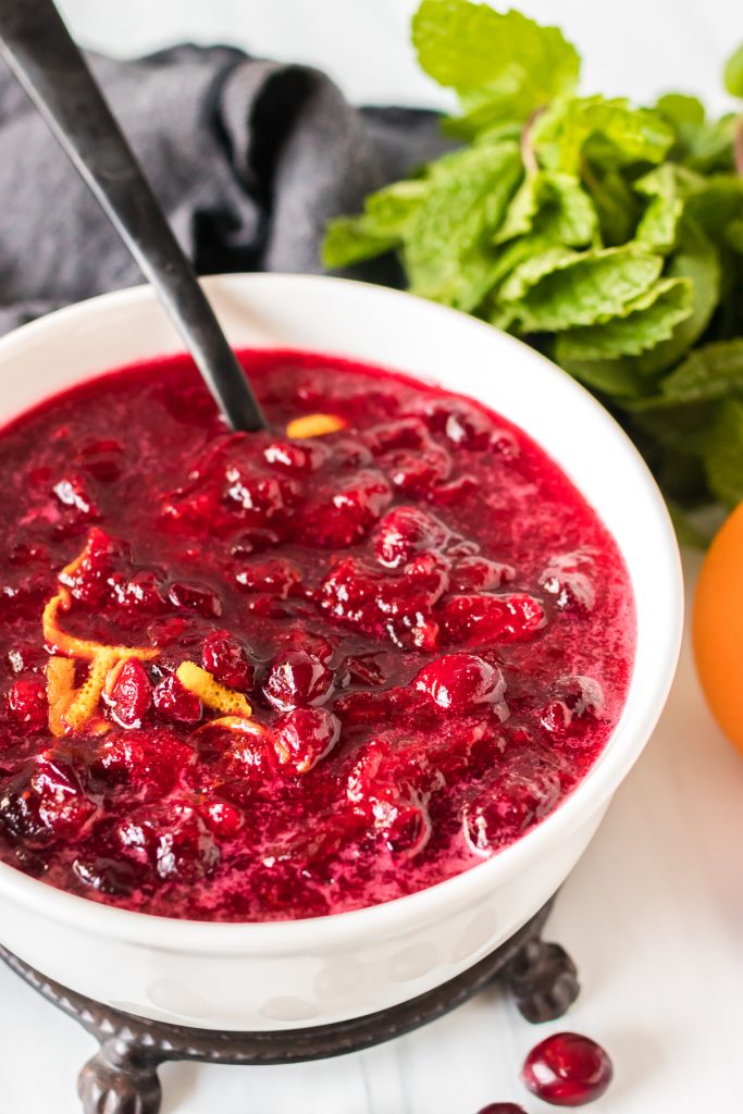 white bowl of cranberry sauce with spoon sticking out