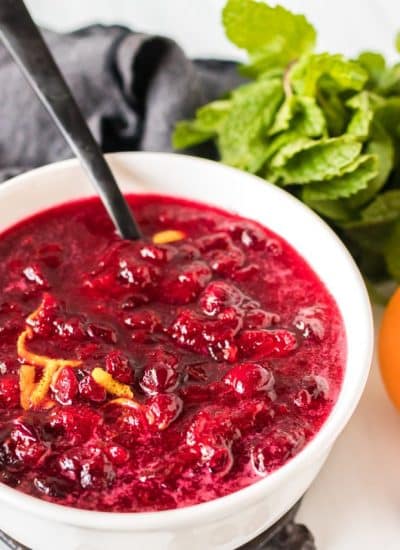 white bowl of cranberry sauce with spoon sticking out