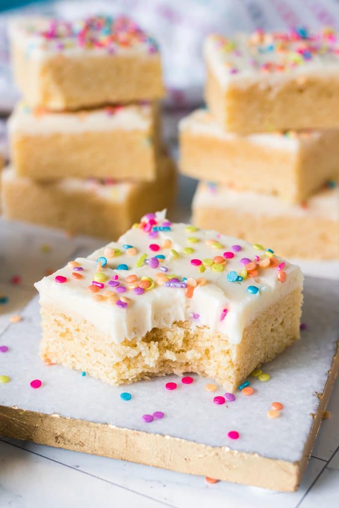 a frosted sugar cookie bar with a bite taken out of it.