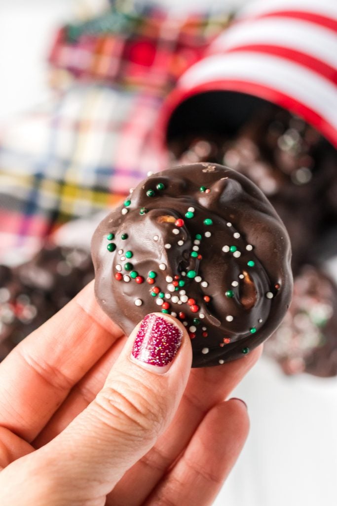 hand holding up a chocolate candy with christmas sprinkles