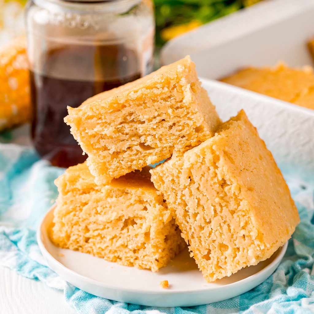 white plate of slices of cornbread with honey jar in background