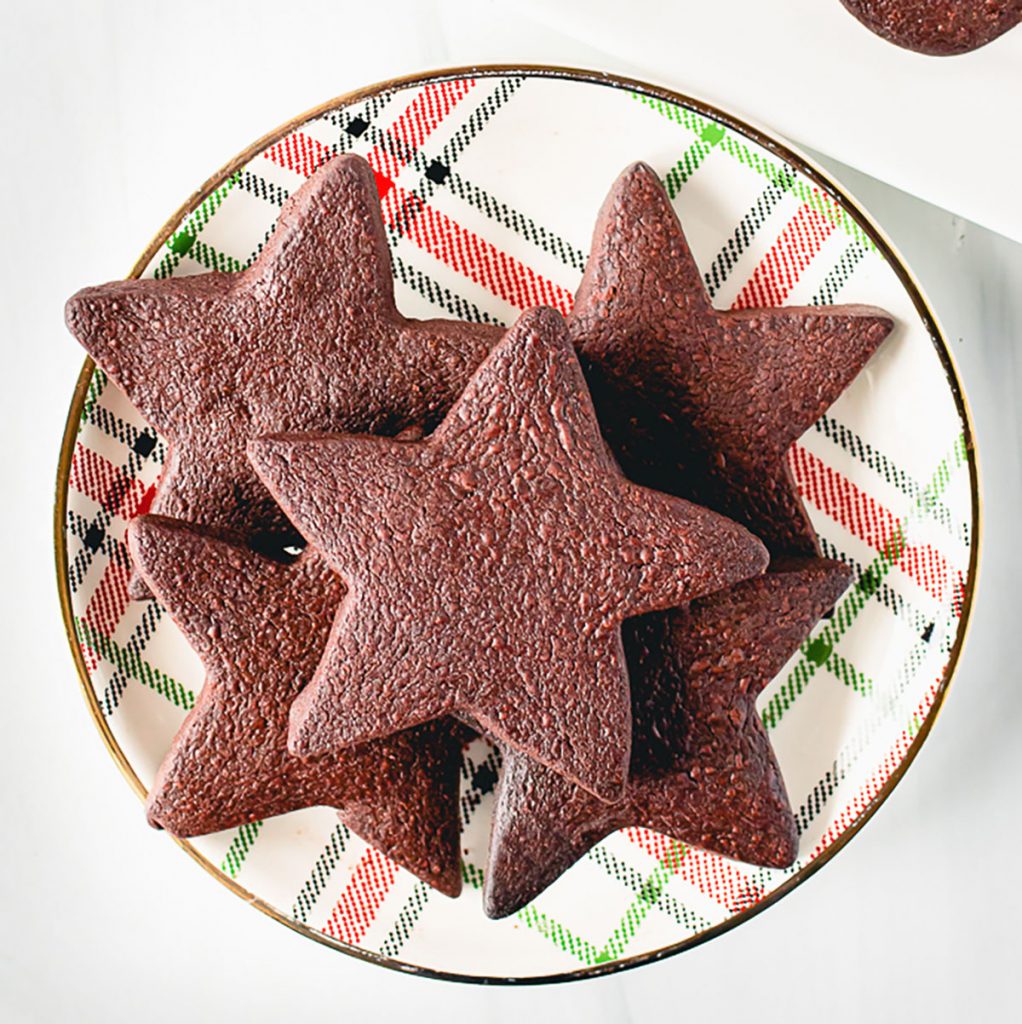 stack of star shaped chocolate shortbread cookies on a tartan Christmas plate