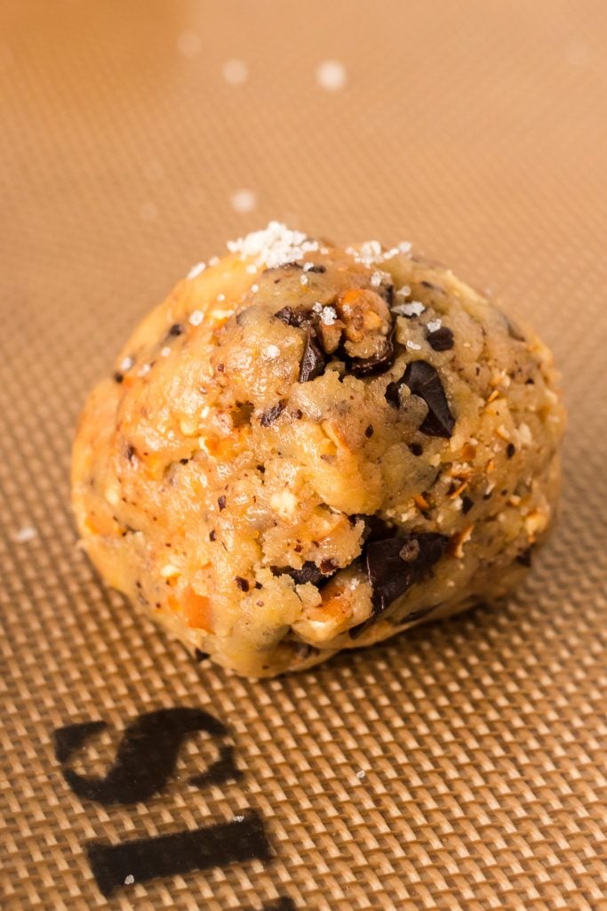 ball of cookie dough sprinkled with sea salt on a silicone mat