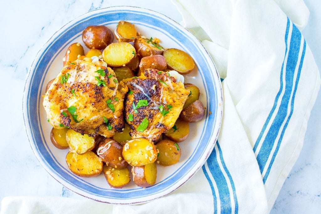 blue rimmed plate of garlic chicken and potatoes