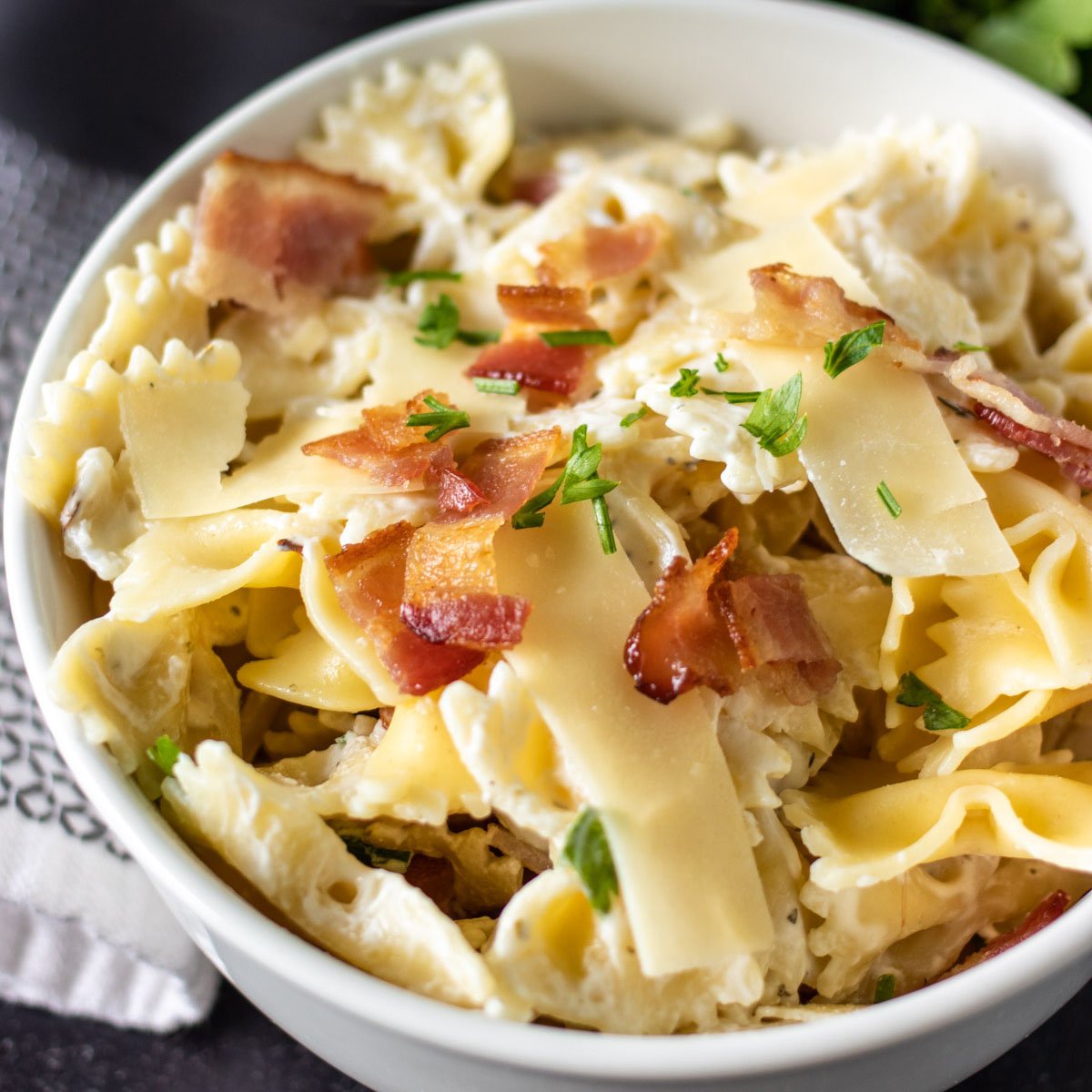 white bowl of bow tie pasta topped with crumbled bacon