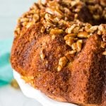 side view of a butter pecan bundt cake on a white cake plate