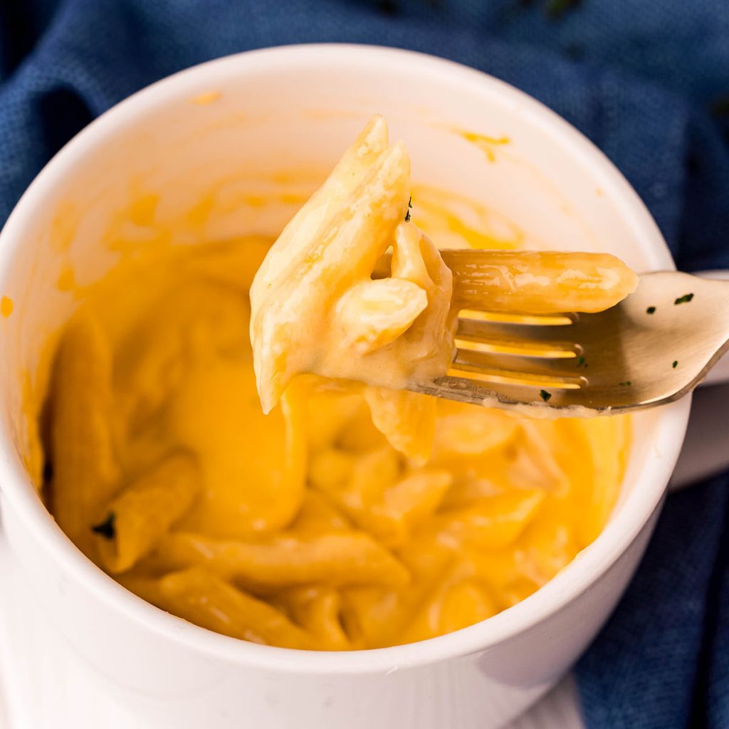 bite of mac n cheese on a fork from a mug