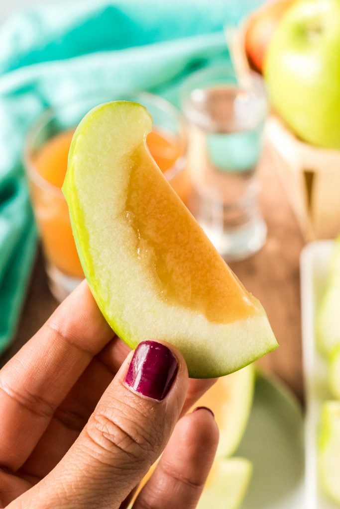 hand holding a slice of caramel apple jello shot made in a green apple