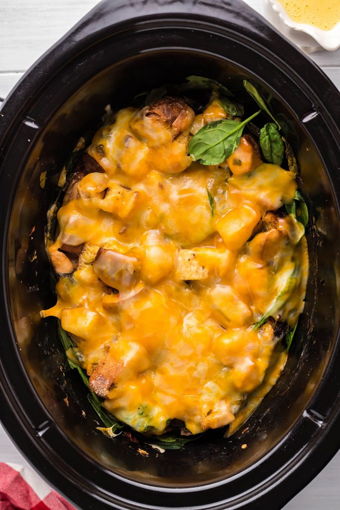 overhead shot of cheesy eggs benedict casserole in a slow cooker