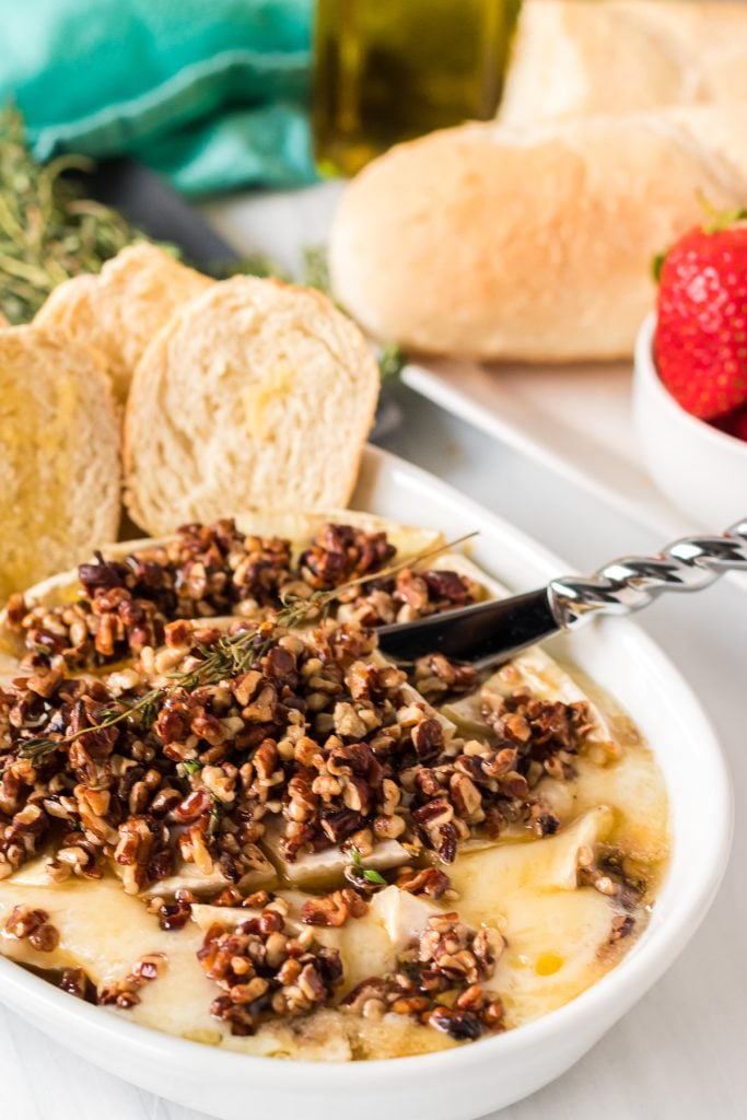 baked brie topped with pecans & honey with a cheese knife stuck in
