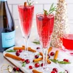 two red cocktails in champagne flutes garnished with cranberries