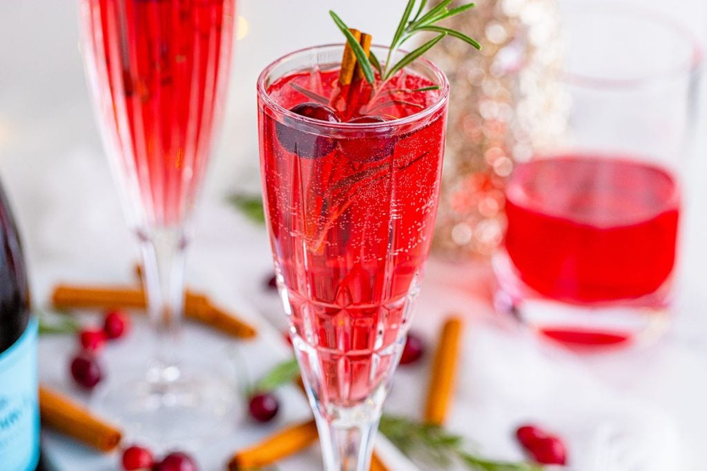 red christmas mimosas surrounded by cinnamon sticks and cranberries