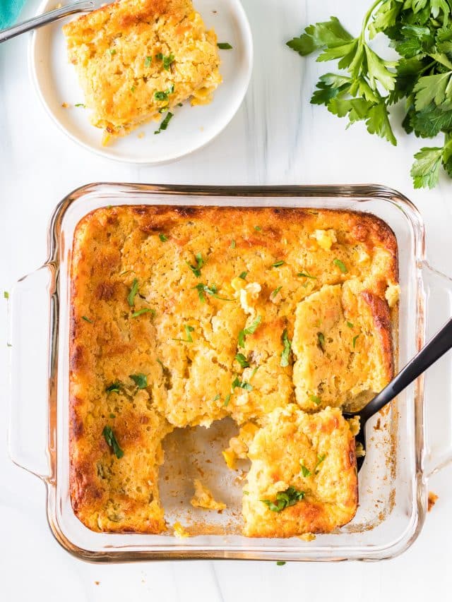 overhead shot of corn casserole with a black spoon in a baking dish