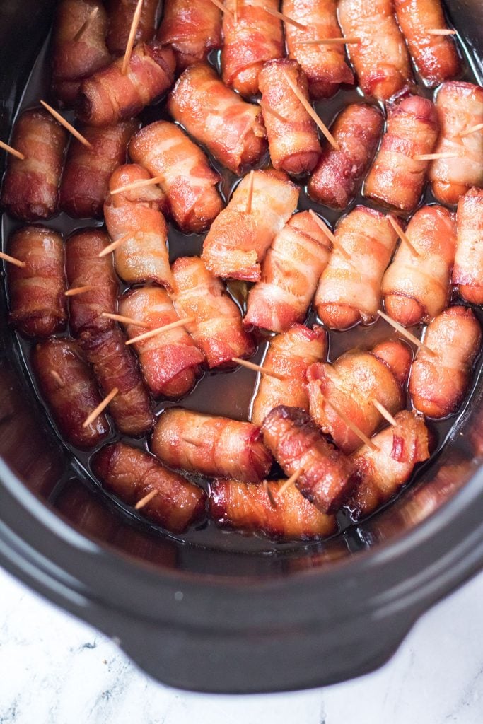 overhead shot of bacon wrapped little smokies in a crock pot with toothpicks holding them together