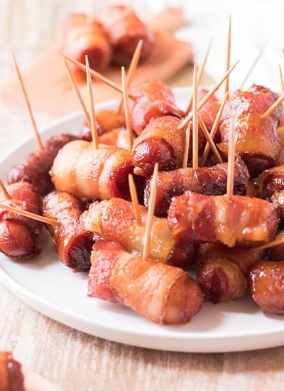 white plate stacked with bacon wrapped smokies held together by toothpicks