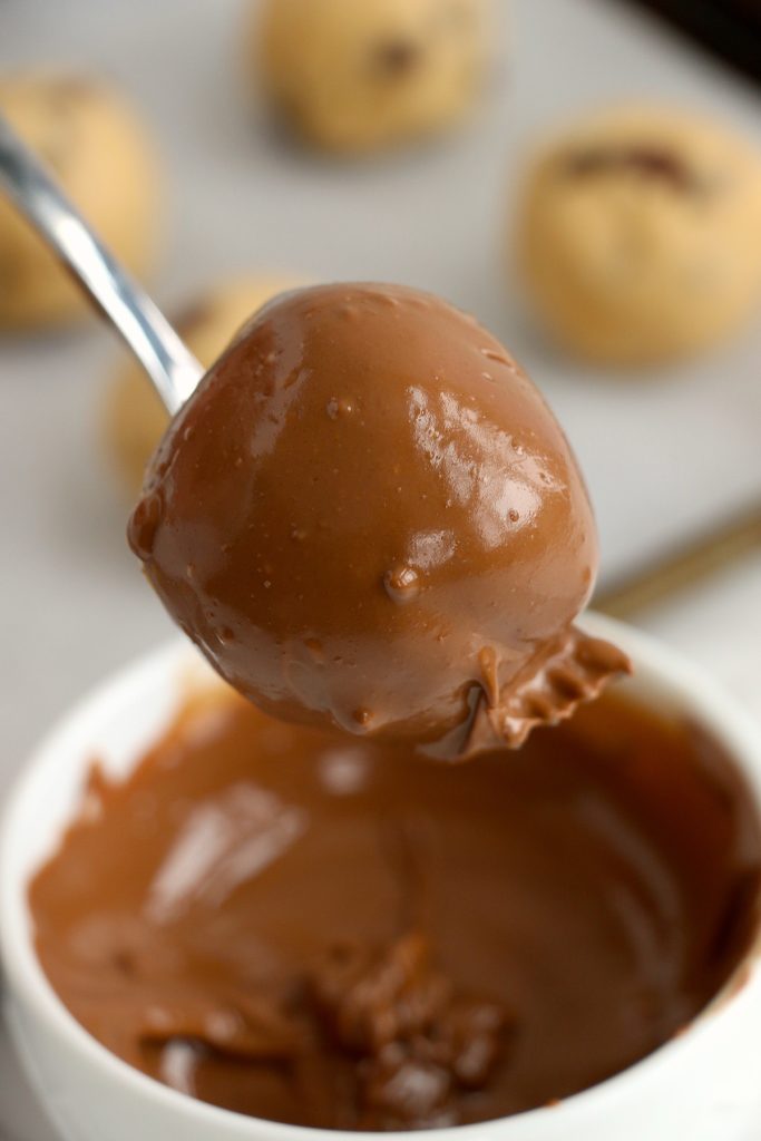 a fork dipping a truffle into melted chocolate