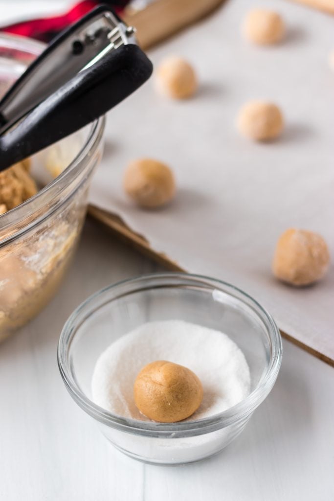 peanut butter cookie dough ball rolling in granulated sugar