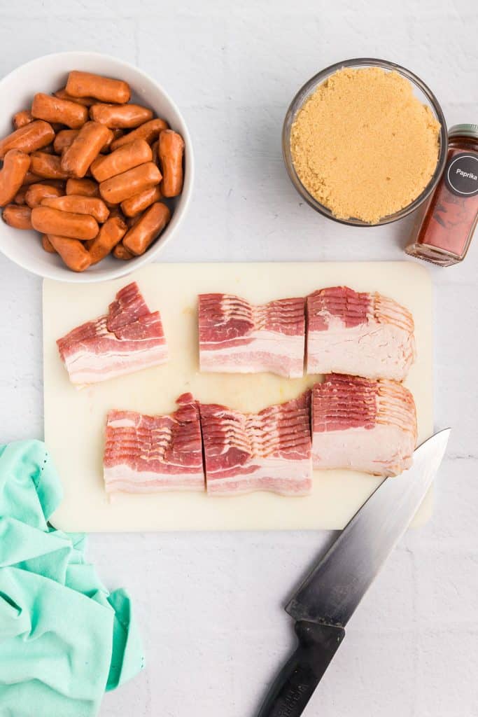 overhead shot of sliced raw bacon, sausages, and brown sugar.