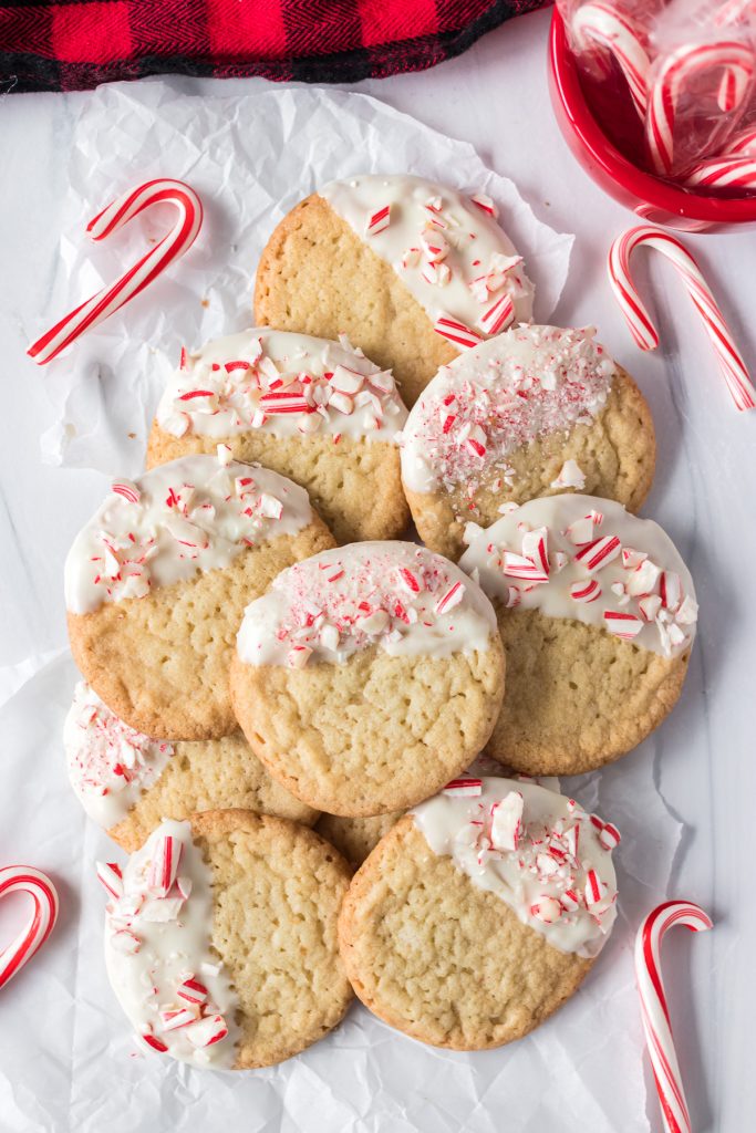 pile of white chocolate dipped sugar cookies surrounded by candy canes