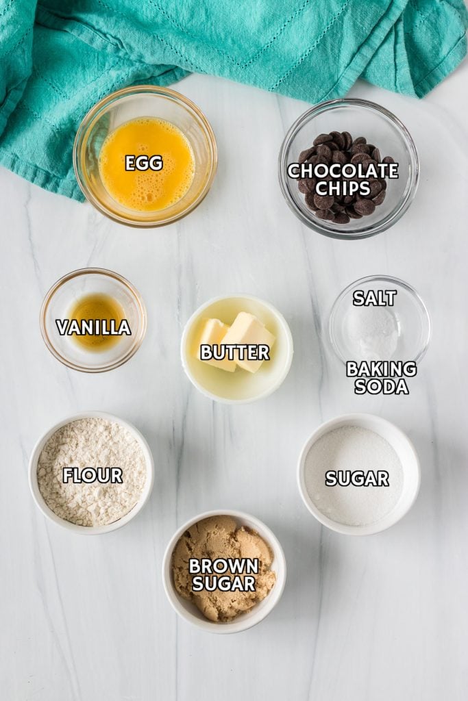 labeled ingredients laid out to make a chocolate chip cookie in the microwave