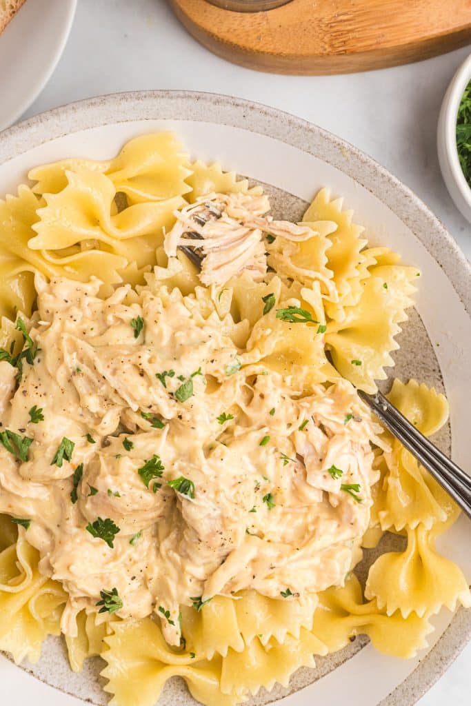 plate of creamy italian chicken on top of bow tie noodles.