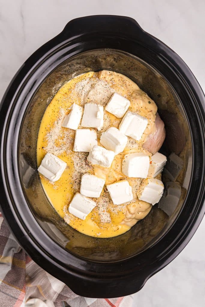 overhead shot of cubed cream cheese in a black crockpot.