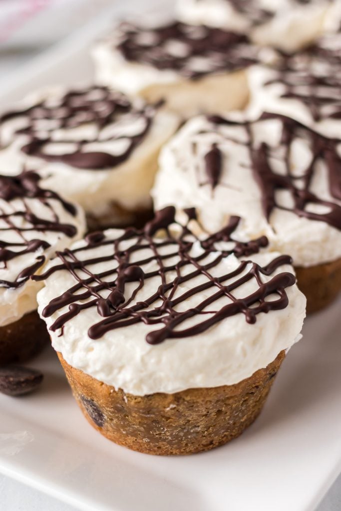 cheesecake cookie cup drizzled with chocolate on a white plate.