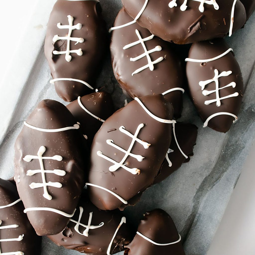 closeup of chocolate covered peanut butter footballs on a plate.