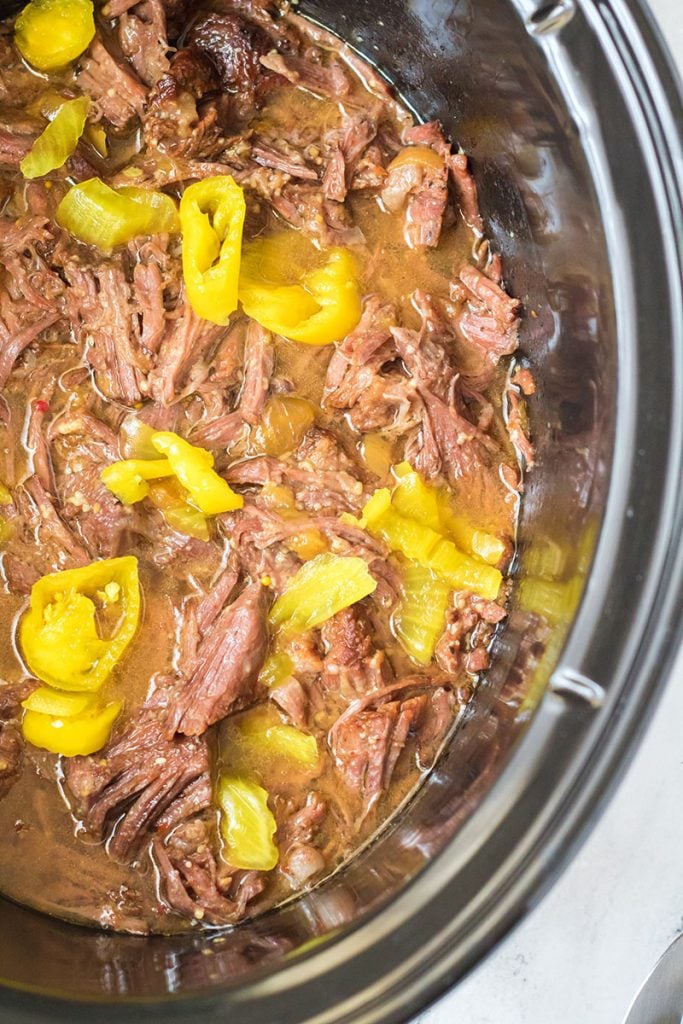 overhead shot of shredded beef and peppers in a crockpot.