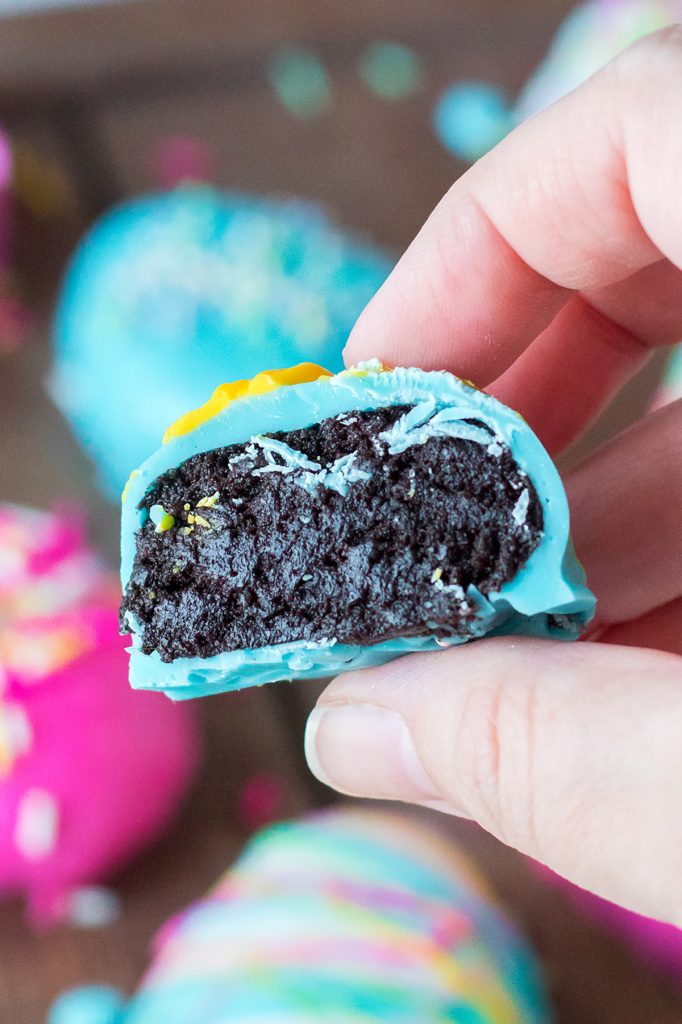 a hand holding an oreo truffle with a blue candy coating.