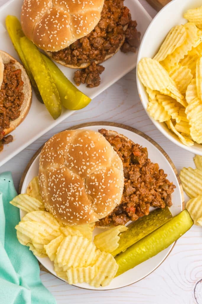 overhead shot of sloppy joe sandwiches with chips & pickles.