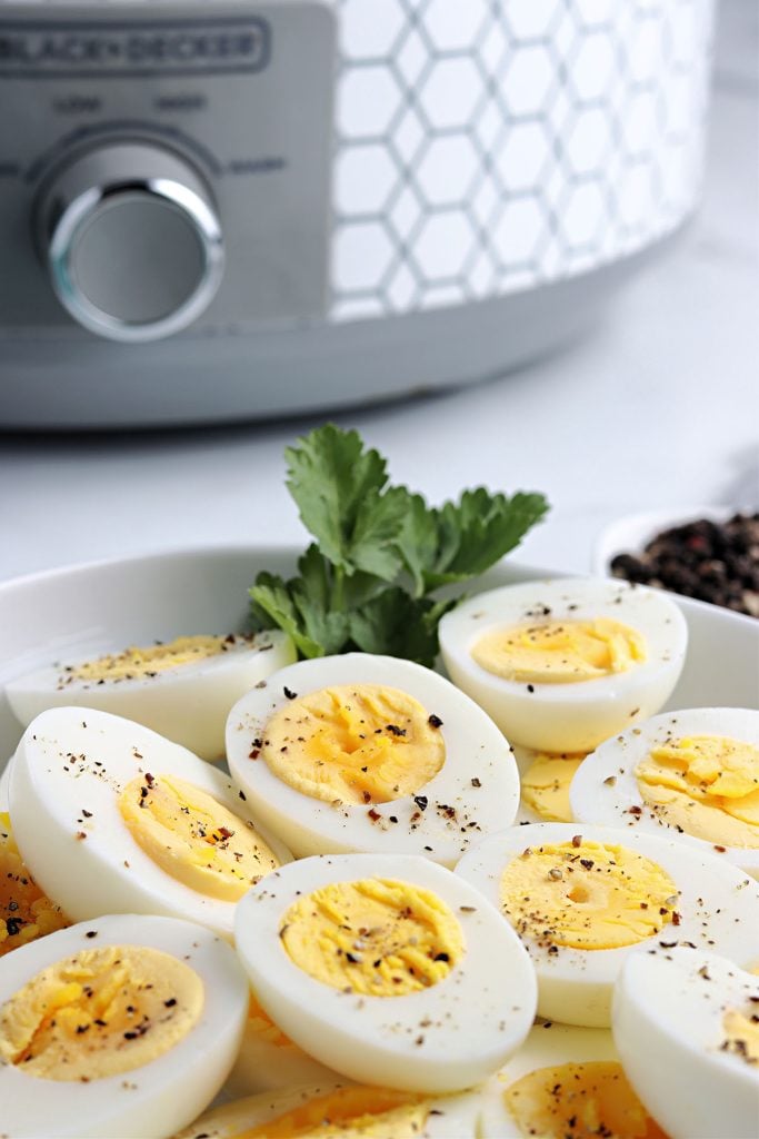 hard boiled eggs on a platter in front of a crockpot.