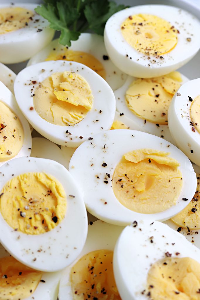 closeup shot of hard boiled eggs sliced in half and topped with pepper.