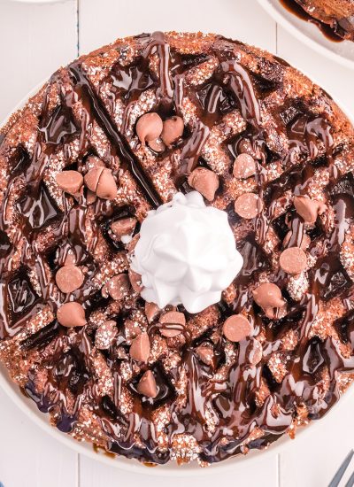 overhead shot of chocolate waffle with chocolate sauce, chocolate chips, and whipped cream.