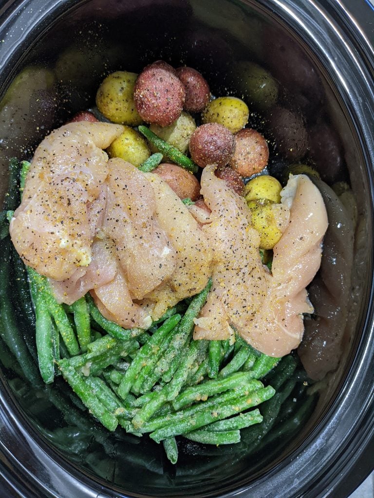 overhead shot of chicken, potatoes, and green beans in a hamilton beach slow cooker.