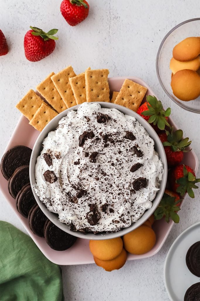 overhead shot of oreo dip on a platter surrounded by cookies and strawberries.