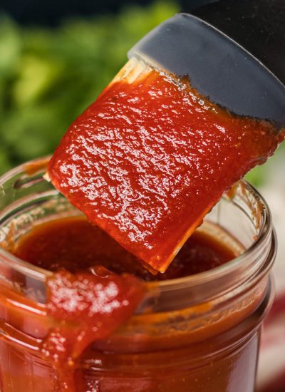 basting brush dipping into jar of honey bbq sauce.