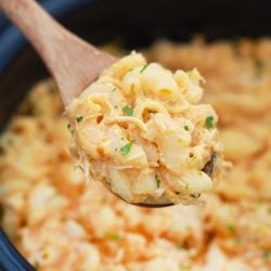 wooden spoon scooping buffalo chicken mac & cheese from a slow cooker.