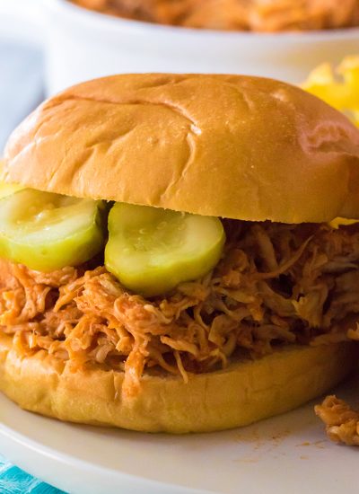 hot honey shredded chicken sandwich on a brioche bun topped with pickles.