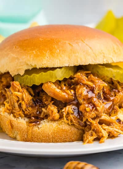 hot honey shredded chicken sandwich on a brioche bun topped with pickles.
