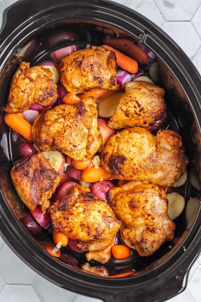overhead shot of chicken thighs in a slow cooker.