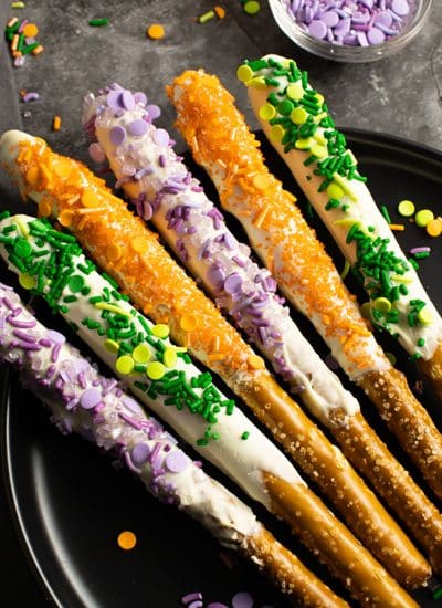 halloween pretzel rods with orange, green, and purple sprinkles.