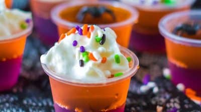 purple and orange jello shot topped with whipped cream & halloween sprinkles.
