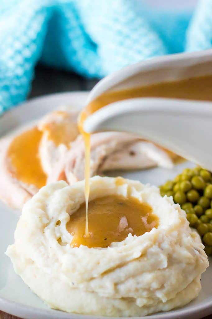 gravy pouring from a boat onto mashed potatoes.