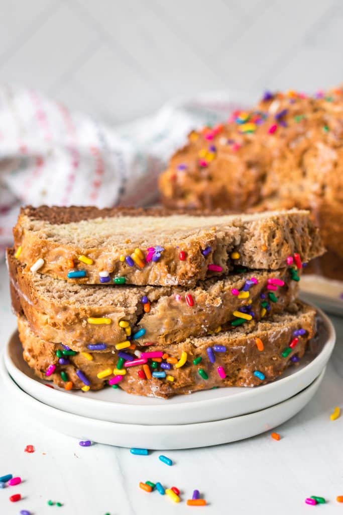 stack of 3 slices of ice cream bread with sprinkles on a white plate.