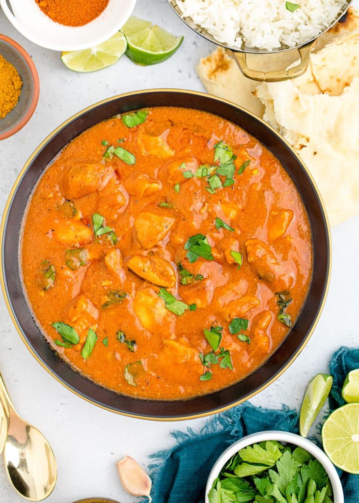 overhead shot of butter chicken in a black bowl topped with cilantro.