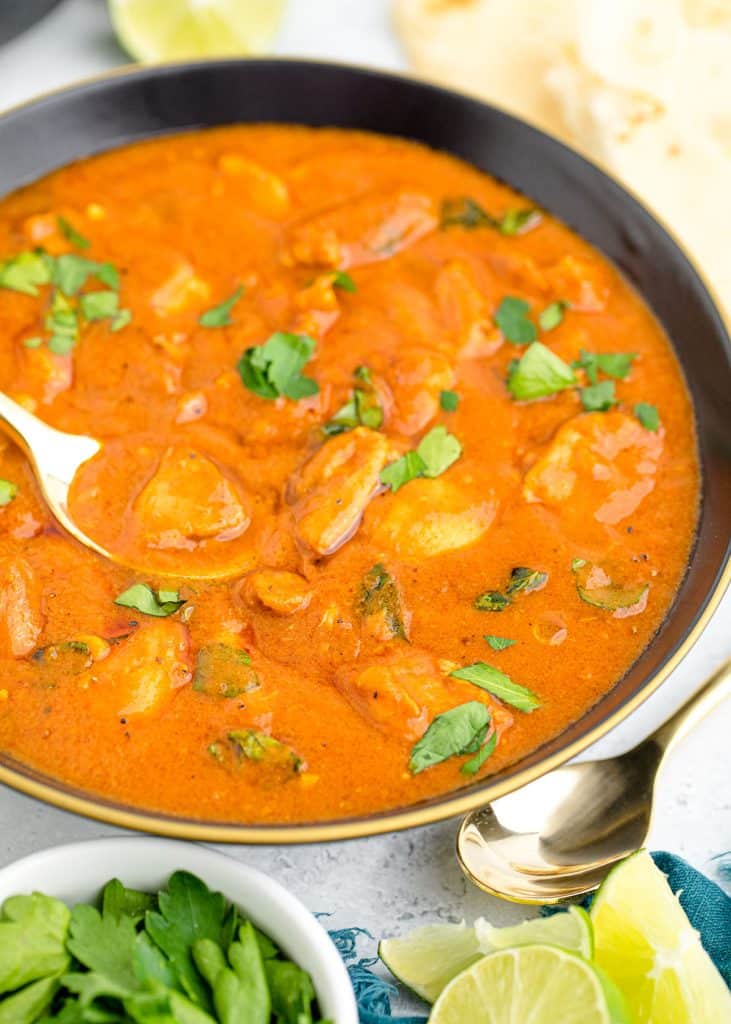 closeup of butter chicken in a bowl with a spoon.