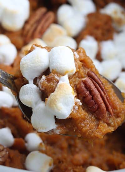 spoon scooping sweet potato casserole from a slow cooker.